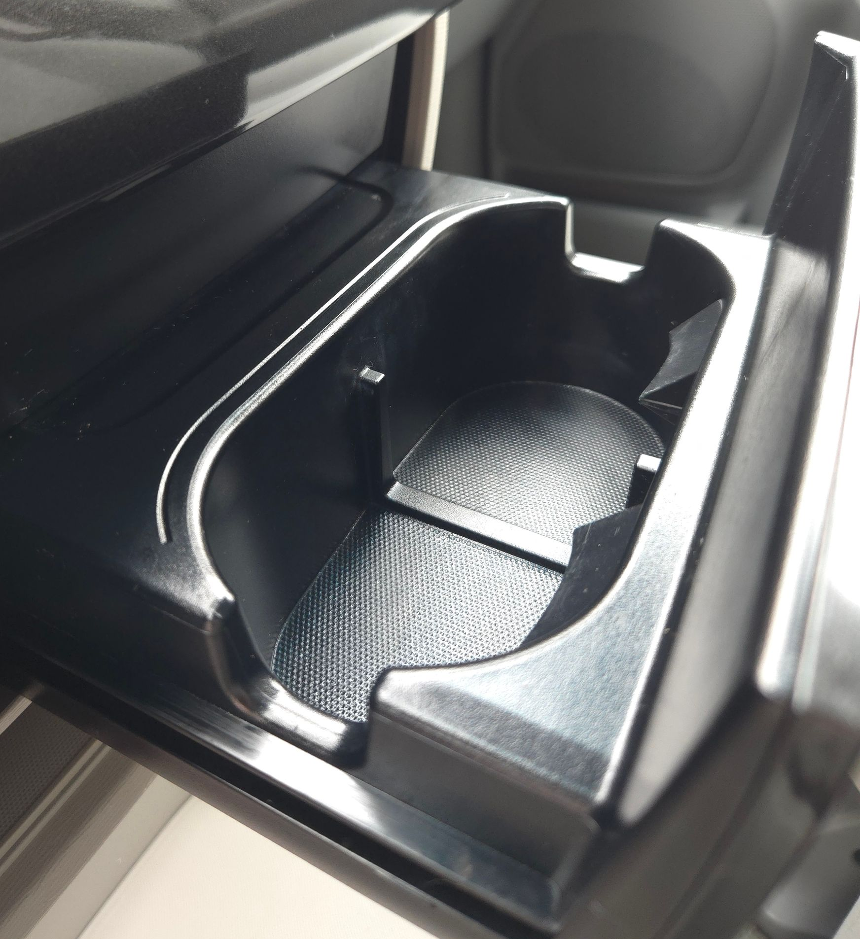 Black car cupholder with textured base, inside a vehicle's console.