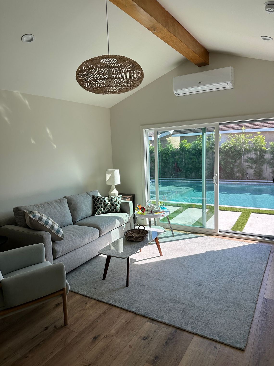 The sunny living area in an accessory dwelling unit (ADU) in-law unit, with sliding glass doors that open up to a backyard pool.