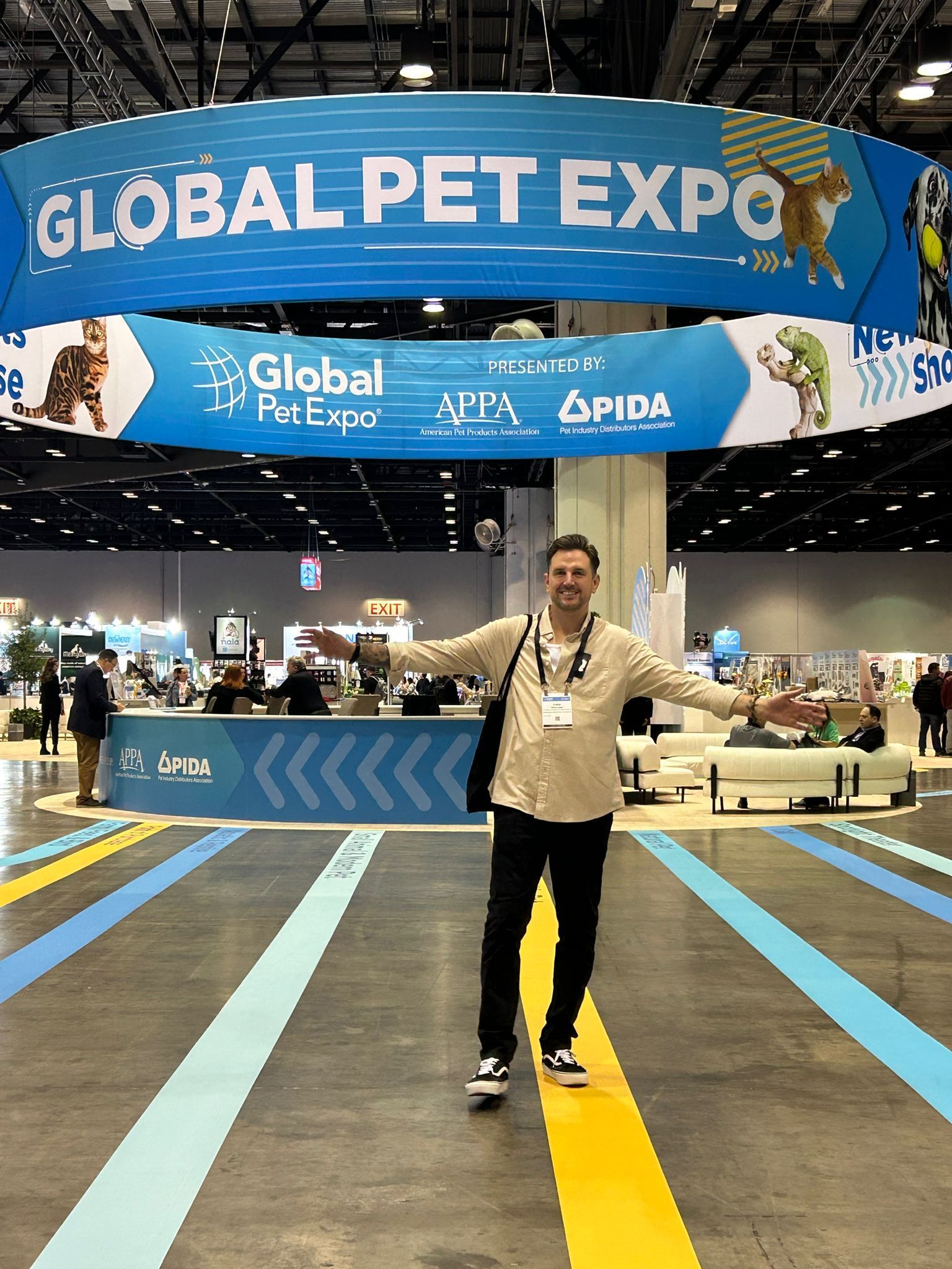 Person posing on a blue-striped aisle at Global Pet Expo under a large blue overhead sign.