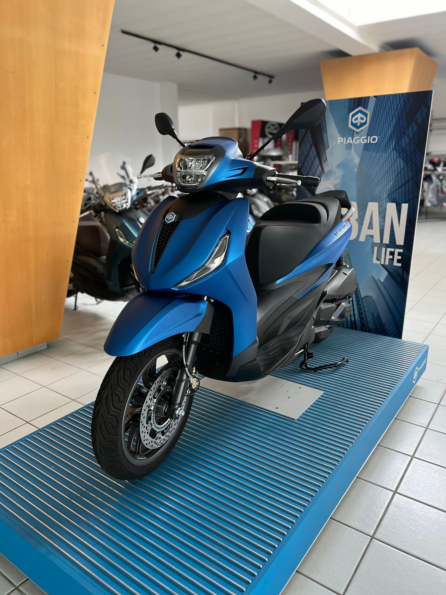 Uno scooter blu è esposto in uno showroom.