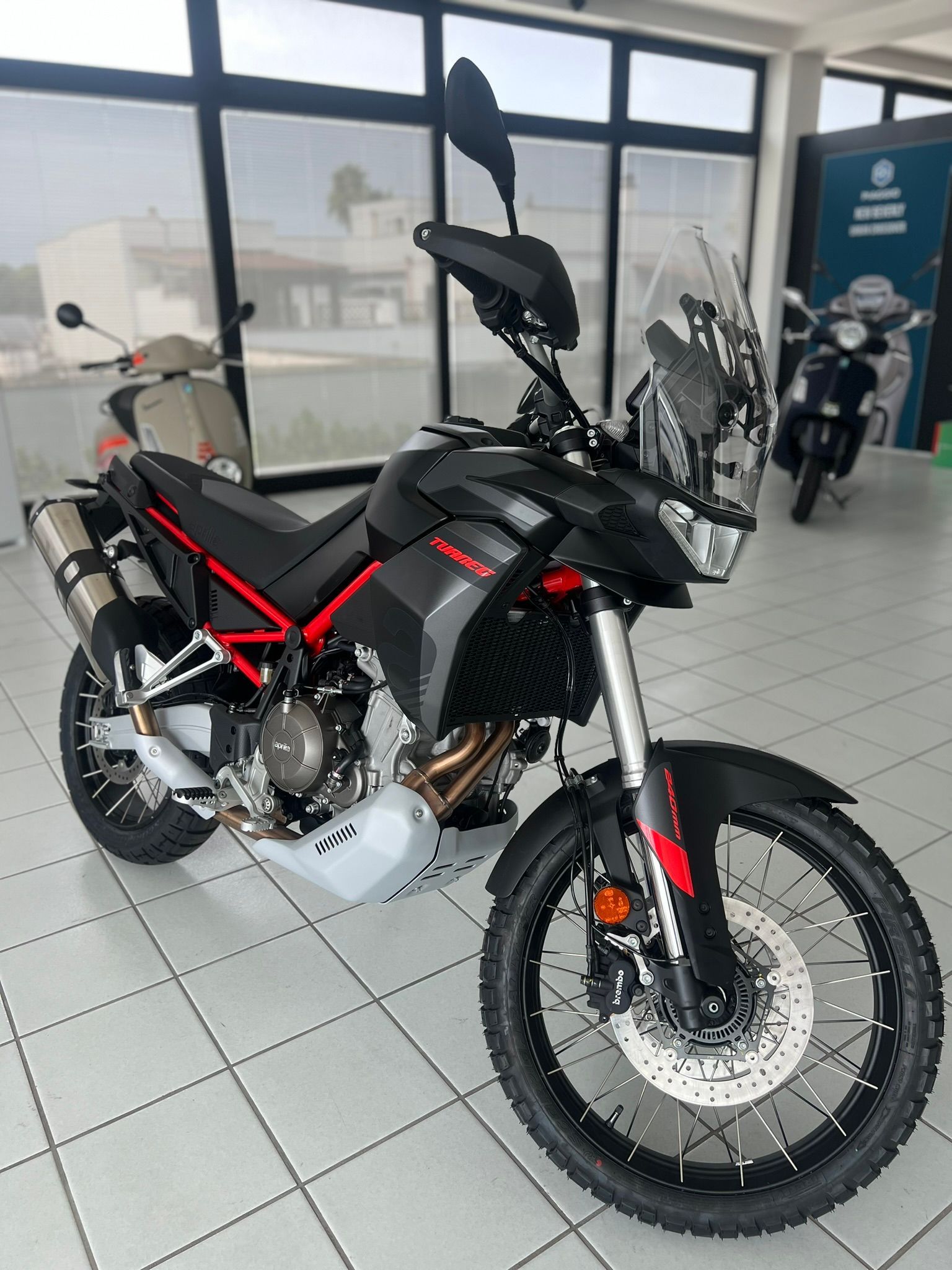 Una moto nera e rossa è parcheggiata in uno showroom.