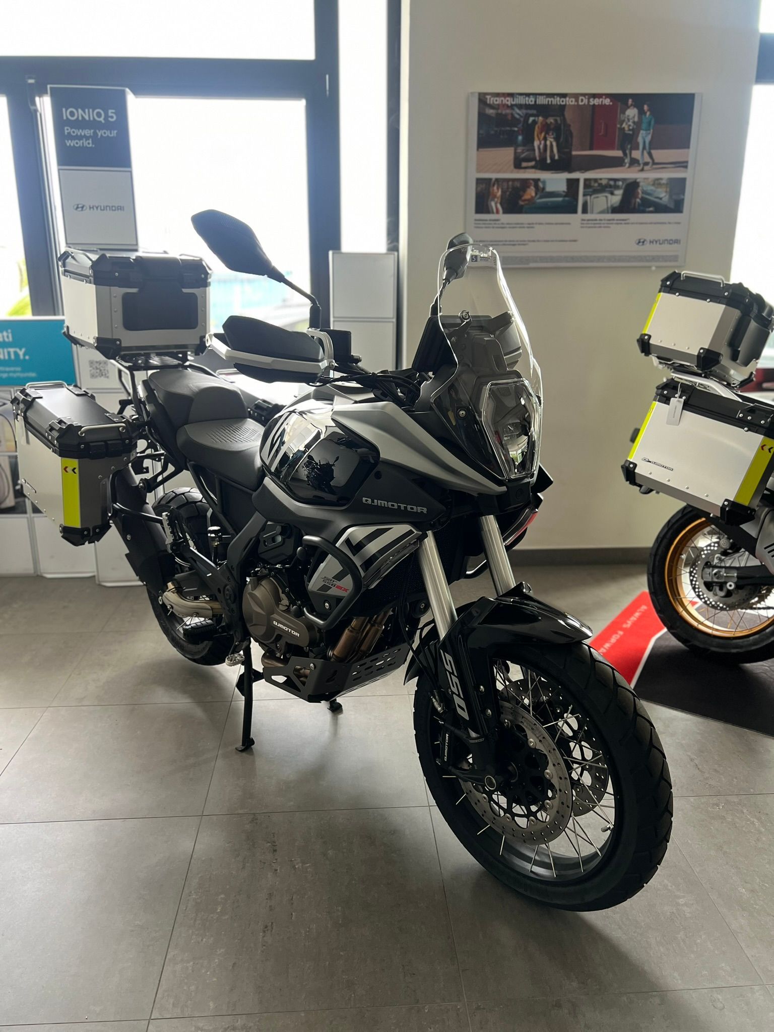 Una motocicletta è parcheggiata in una stanza accanto a una finestra.