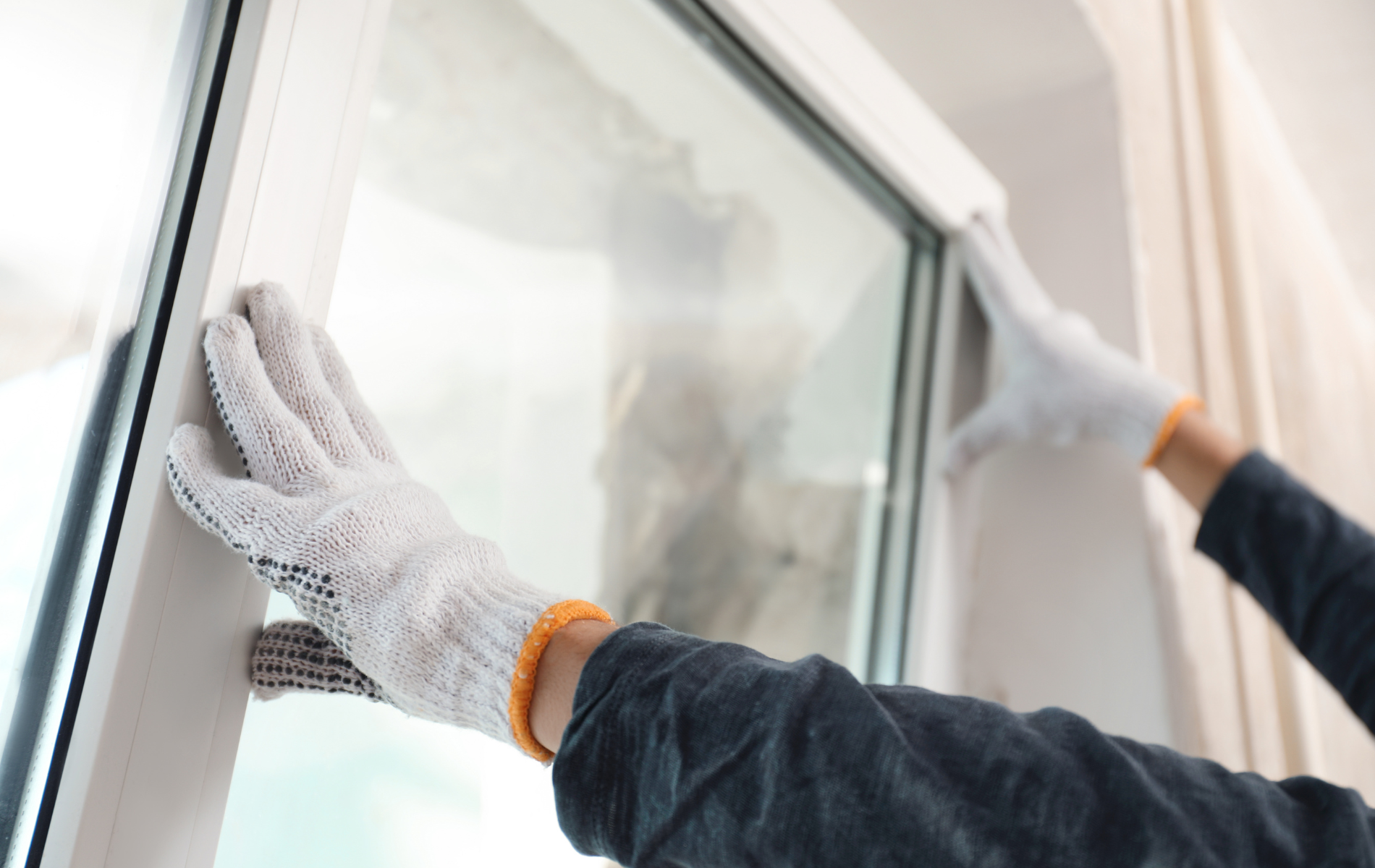 A person wearing gloves is cleaning a window.