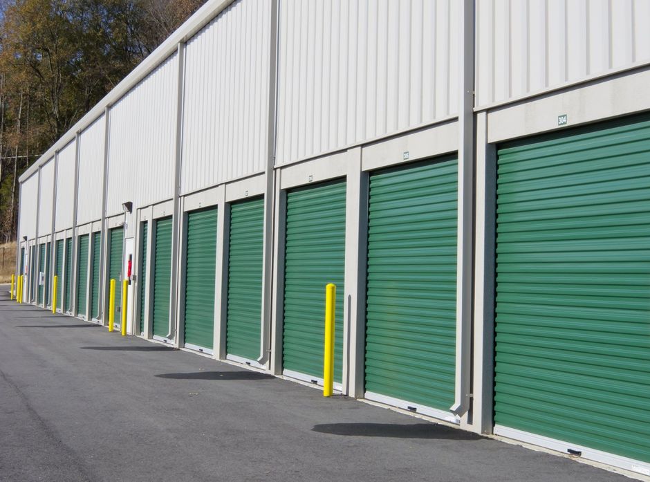 A row of storage units with green doors and yellow poles