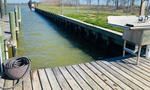 Wooden dock extending into water alongside a dark, wooden bulkhead. A sink sits on the right.