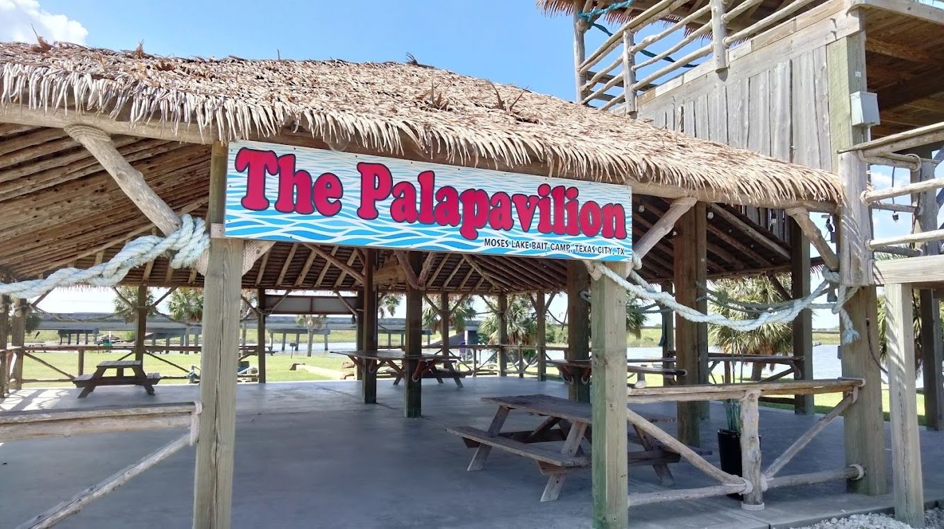 The Palapavilion, a covered pavilion with picnic tables, near water, blue sign.