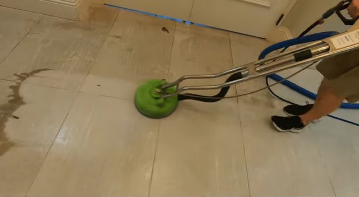 A person is cleaning a tiled wall with a steam cleaner.