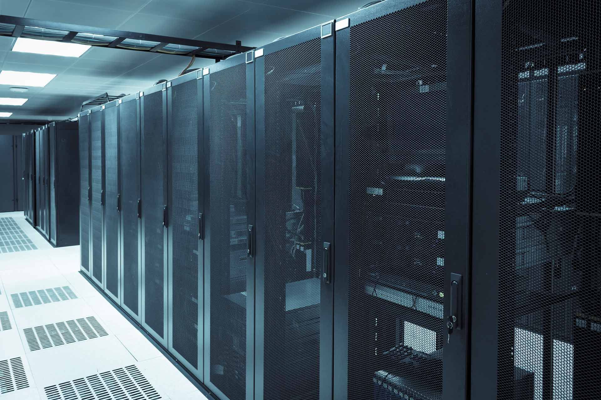 Rows of black server racks in a data center with bright overhead lighting