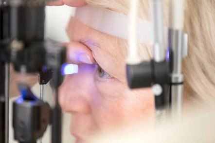 Woman receiving an eye exam using a slit lamp.