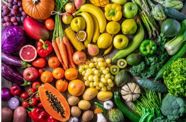 Colorful assortment of fruits and vegetables arranged in a rainbow pattern on a wooden surface.