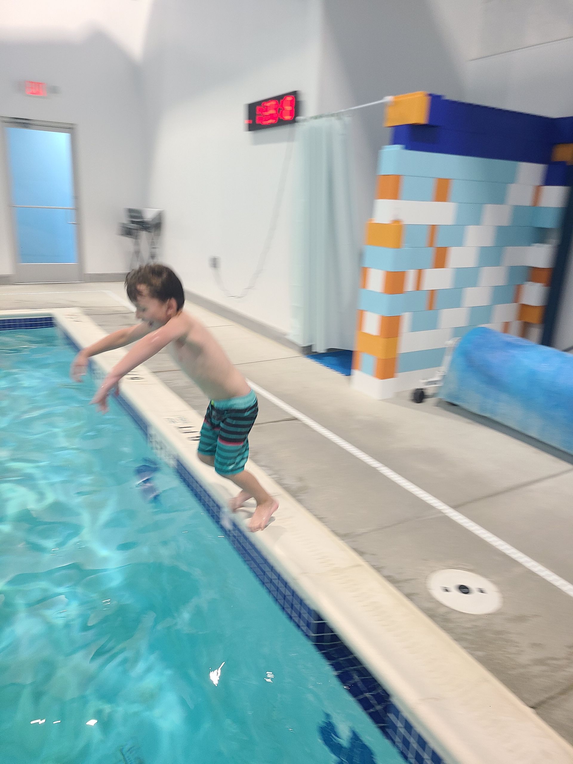 A young boy is swimming underwater in a swimming pool.