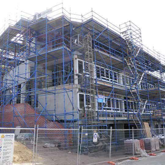 A large building under construction with blue scaffolding around it.