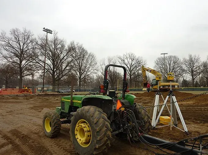 A john deere tractor is parked in a dirt field.