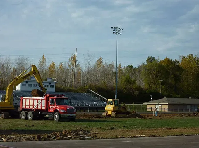 A red dump truck is parked next to a yellow excavator