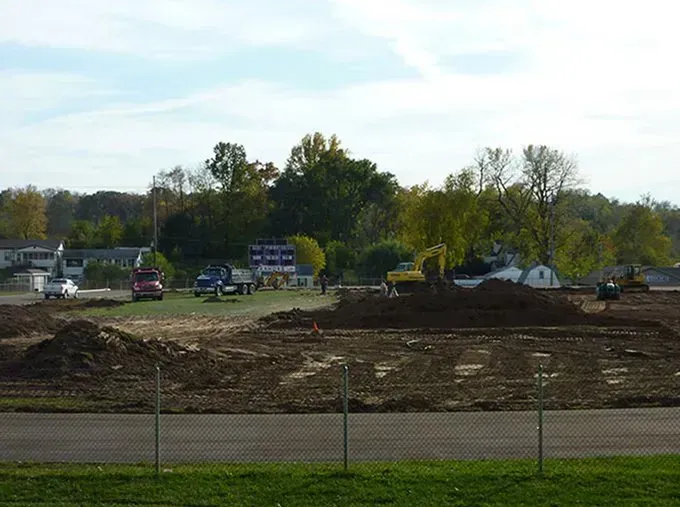 A construction site with a lot of dirt and trucks in the background.