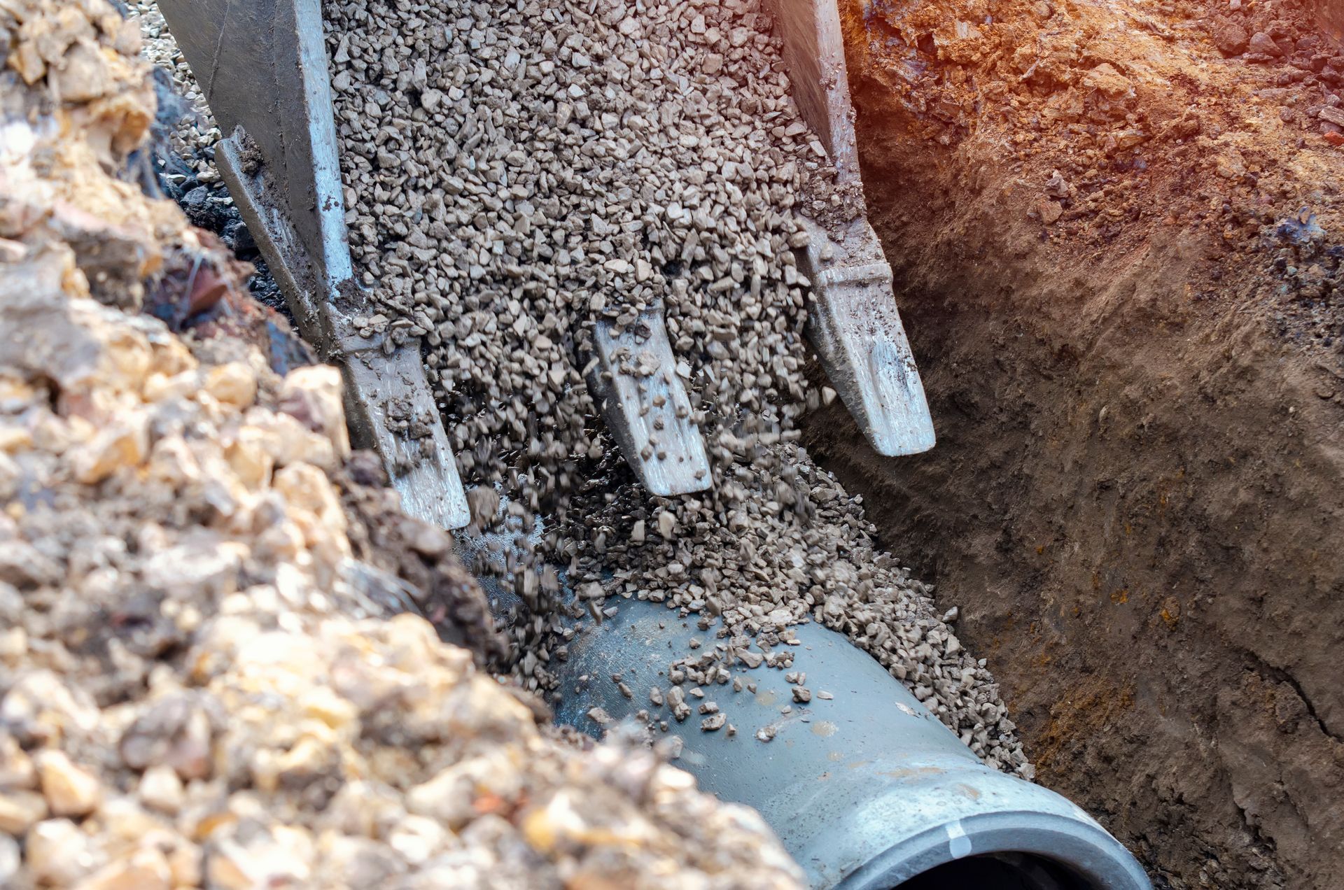 A concrete pipe is being filled with gravel by a bulldozer.