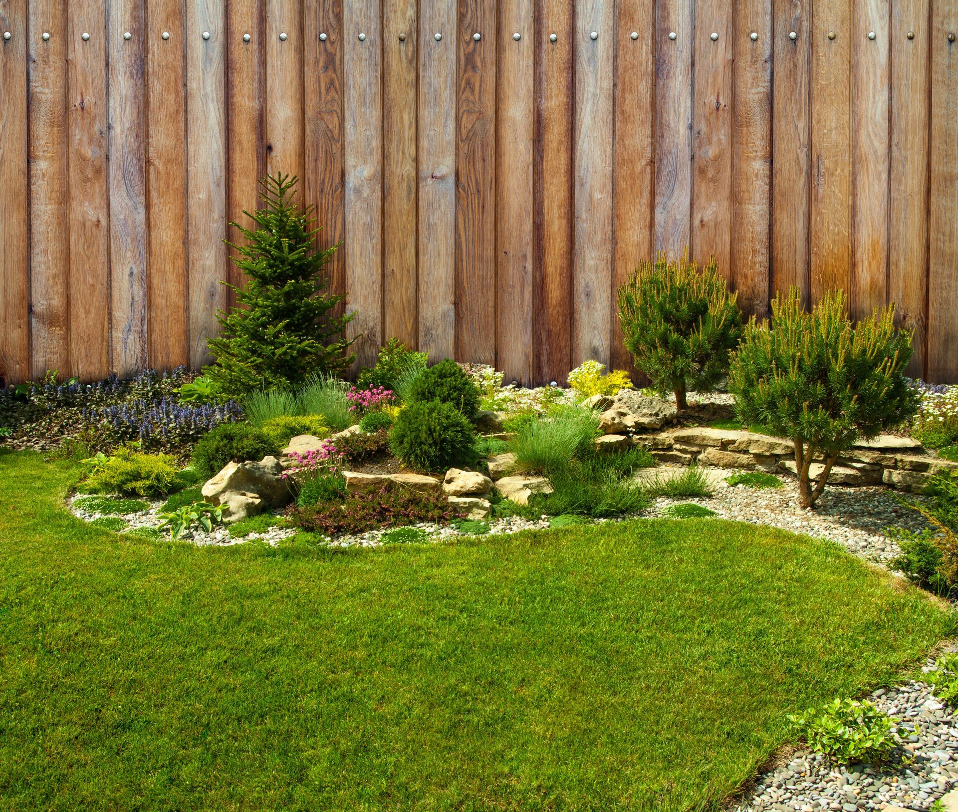 A wooden fence surrounds a lush green garden