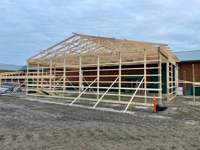 A large wooden structure is being built in a dirt field.