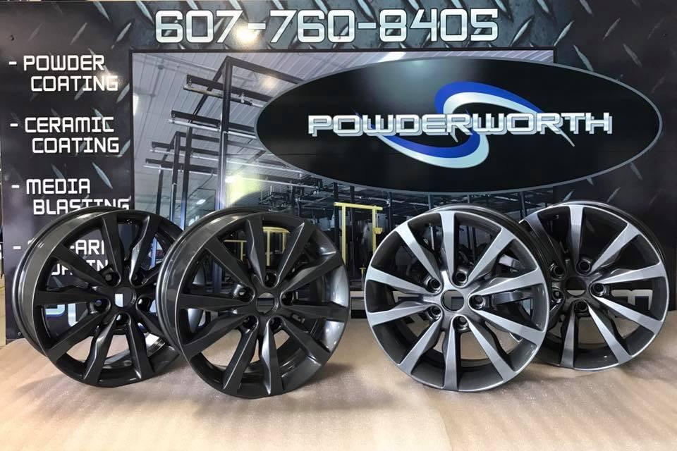Three wheels are sitting in front of a sign that says powder coating