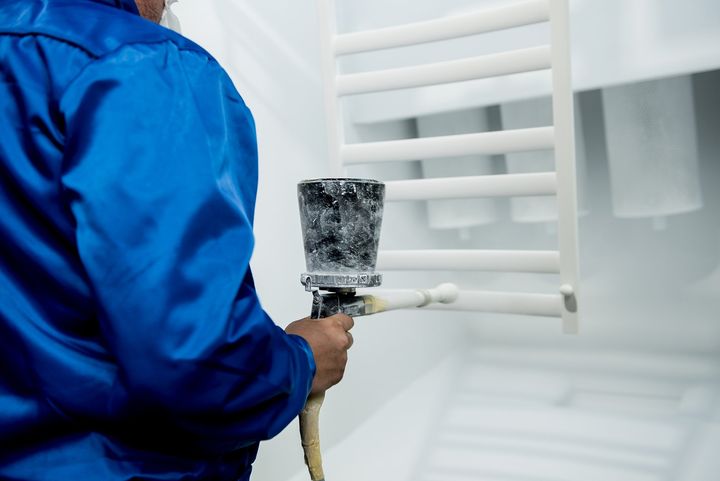 worker performing powder coating metal details