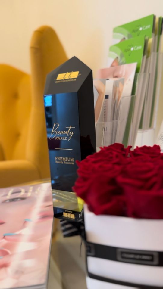 Schwarzer und goldener Parfümflakon mit roten Rosen und Broschüren auf einem Tisch.