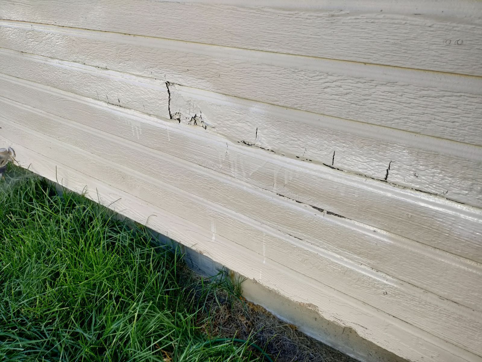 Damaged exterior siding with visible cracks and water damage in need of repair by A1 Handyman in Garden City, ID