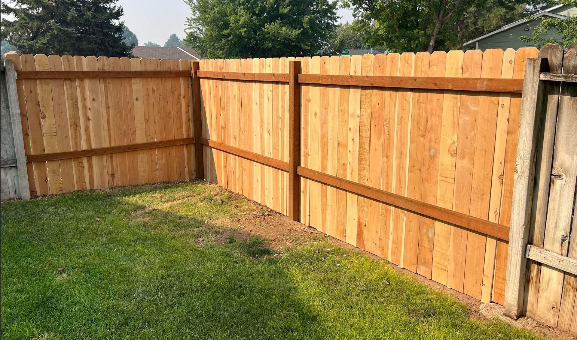 New cedar privacy fence section with wood posts and horizontal rails in a residential backyard in Boise, ID.