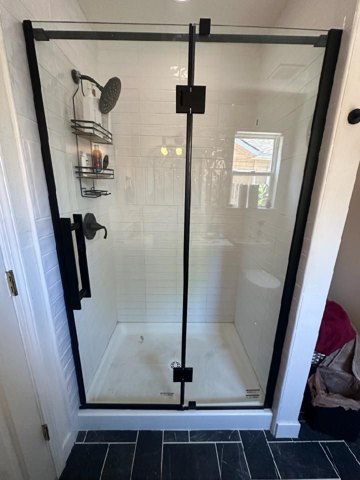 Frameless glass shower door with black hardware professionally installed in a Boise, ID bathroom by A1 Handyman.