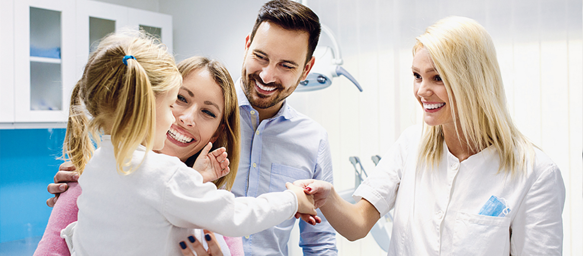 A family is shaking hands with a dentist in a dental office.