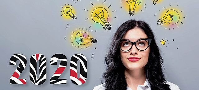 A woman wearing glasses is looking up at a drawing of light bulbs and the year 2020.