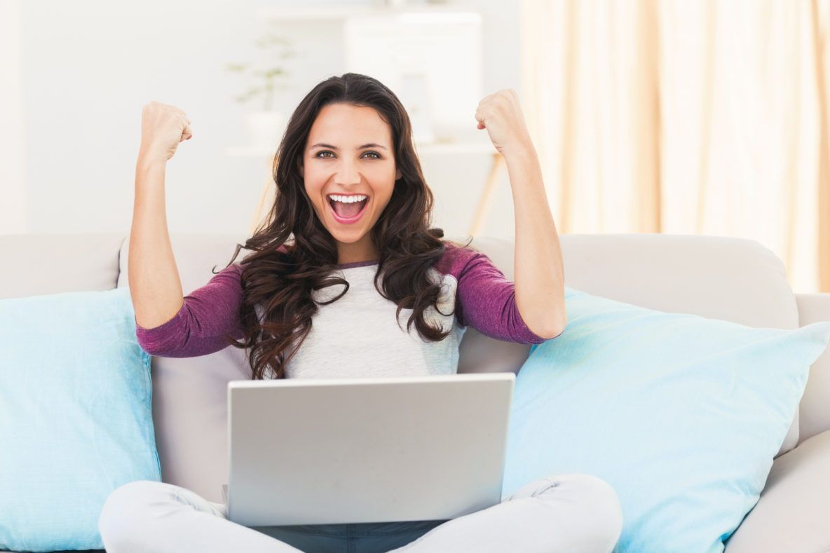 A woman is sitting on a couch using a laptop computer.