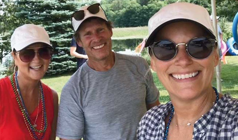 A man and two women are posing for a selfie in a park.