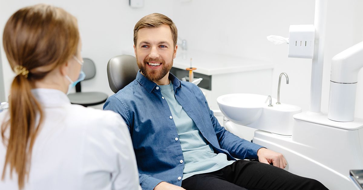 Smiling male patient talking to dentist in a dental chair.