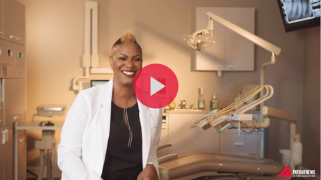 A woman in a lab coat is standing in front of a dental chair.