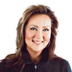 A woman in a black jacket is smiling for the camera.