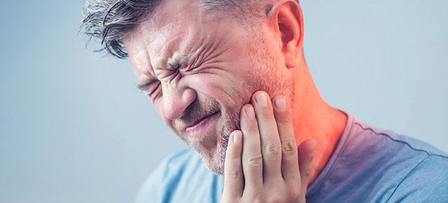 A man is holding his face in pain because of a toothache.