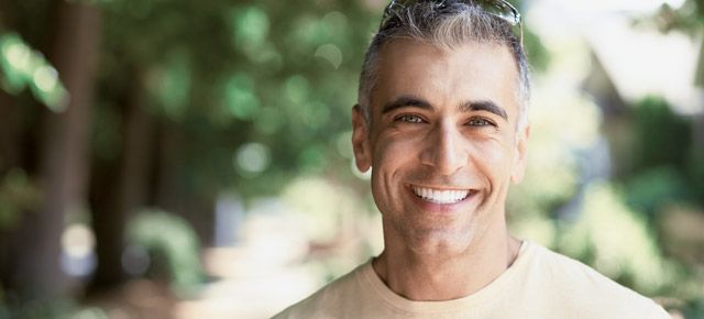 A man is smiling for the camera in a park.
