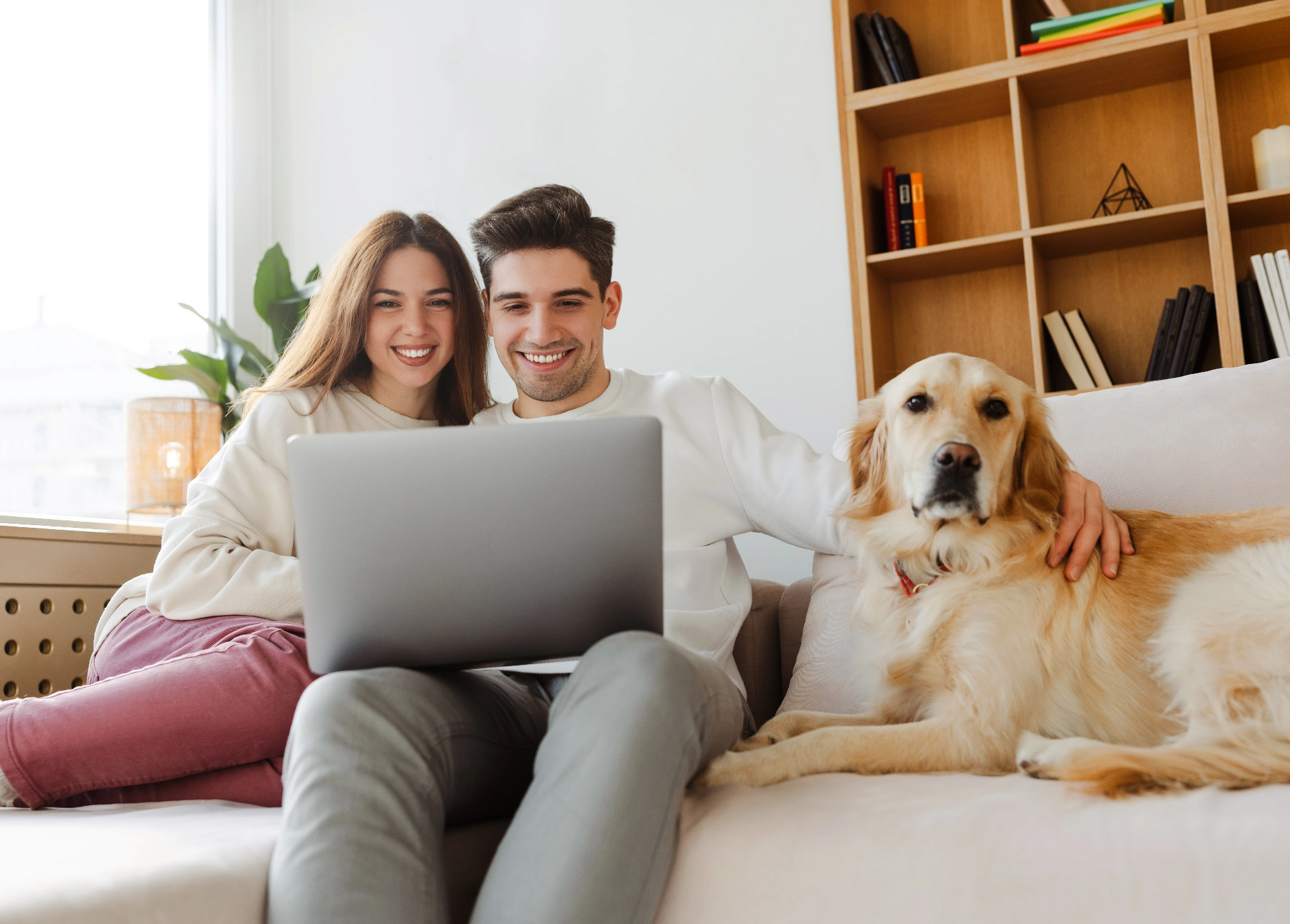Couple using a laptop at home with their dog.