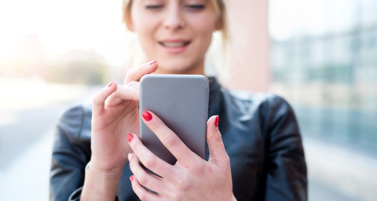 A woman with red nails is using a cell phone.