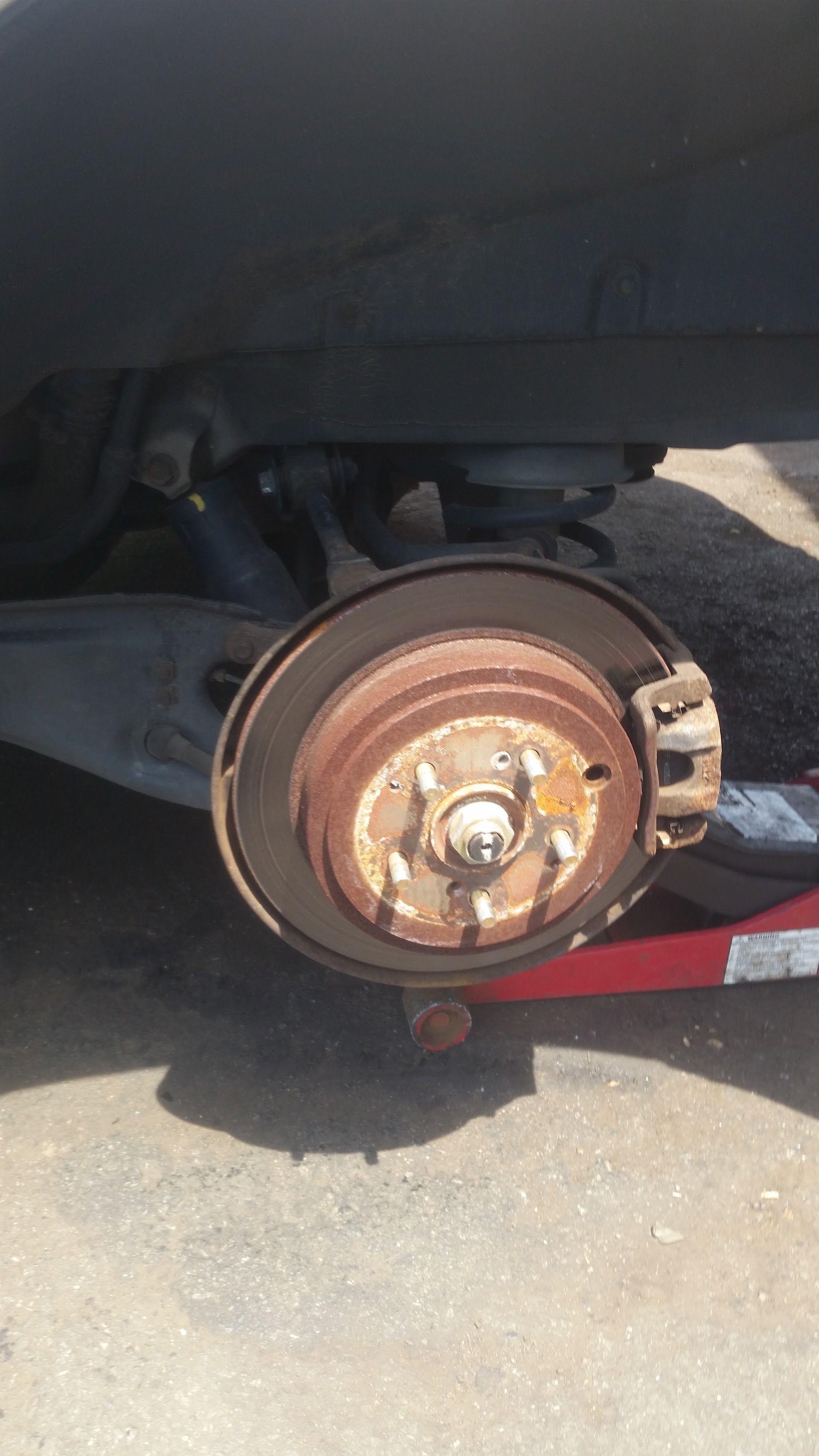 Rear car wheel with brake rotor and caliper assembly; rusted metal. | D & D Auto Clinic
