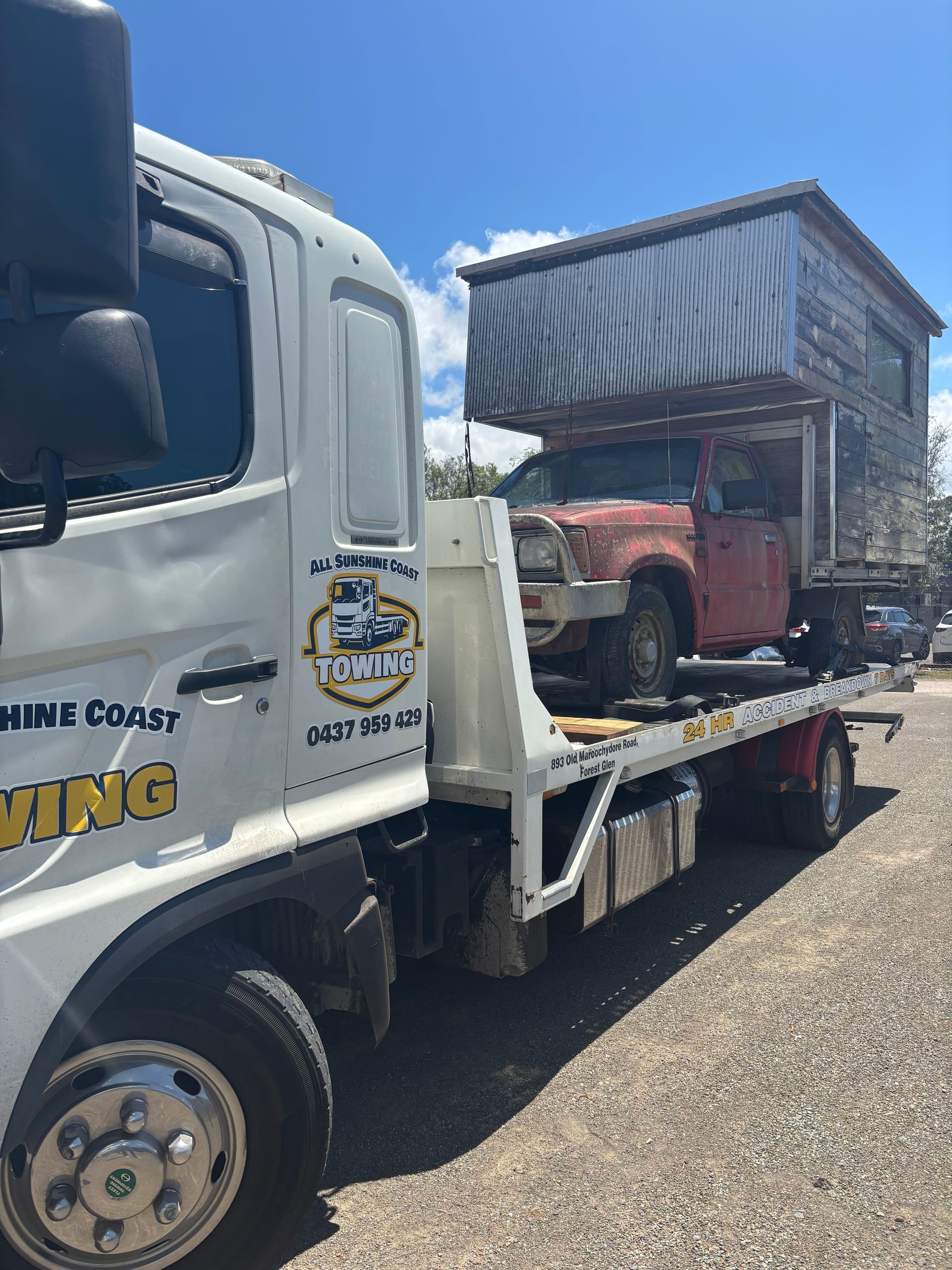 Tow truck hauling an old red vehicle on a flatbed under a blue sky — All Sunshine Coast Towing In Sippy Downs, QLD