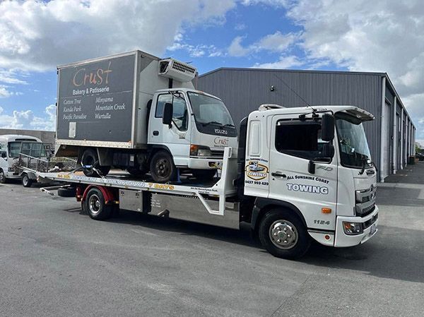 Two White Tow Trucks Carrying a Grey Box Truck in an Industrial Lot — All Sunshine Coast Towing In Forest Glen, QLD