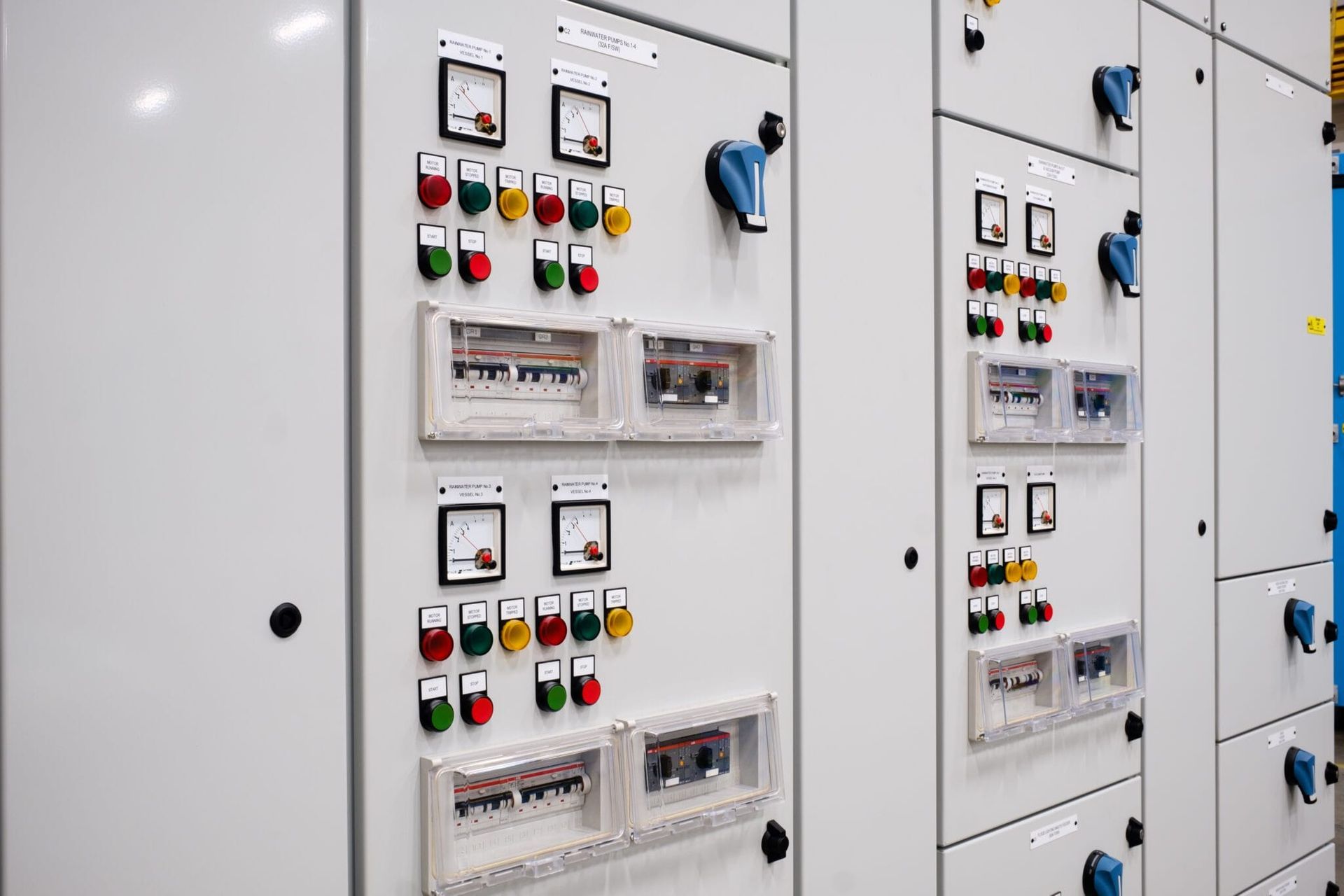 Zwei industrielle elektrische Schaltschränke mit mehreren analogen Messgeräten, farbigen Druckknöpfen und transparent abgedeckten Leistungsschaltern.