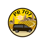 Circular logo: a black van on a yellow and brown landscape with buildings and