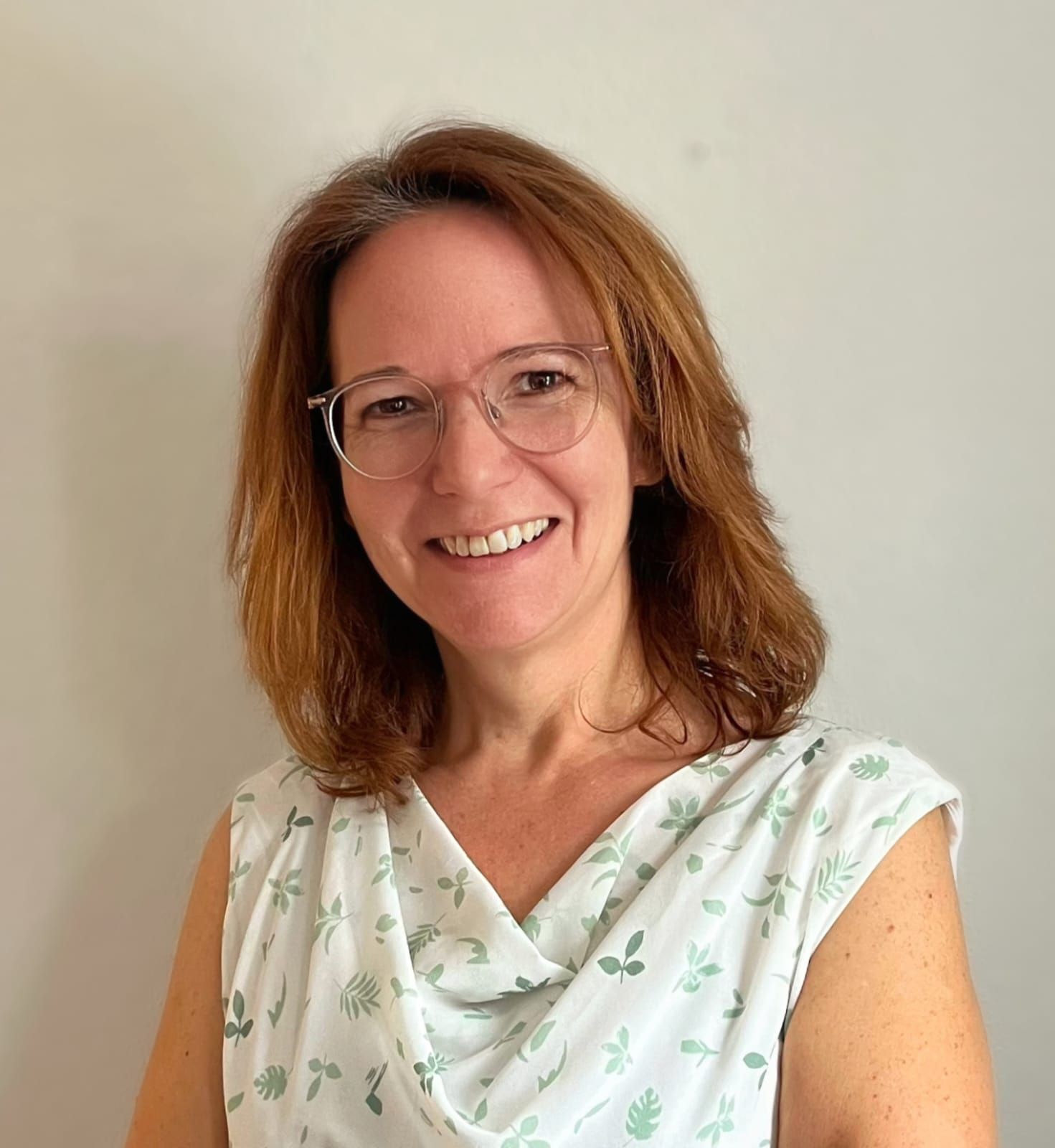 Porträt Sonja Weinberger, freundlich lächelnde Frau mit Brille, Schulterlanges hellbraunes Haar, sommerliches Oberteil
