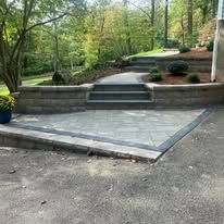 Curved cobblestone garden path beside patio chairs, table, and lush landscaping.