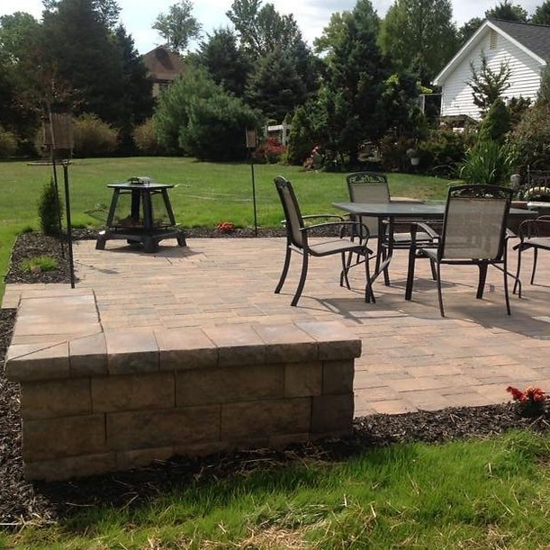 Wicker patio seating with beige cushions and a wooden coffee table on a stone terrace