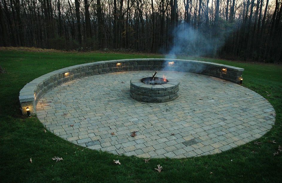 Curved stone garden path beside a lush green lawn and flowering shrubs between white houses