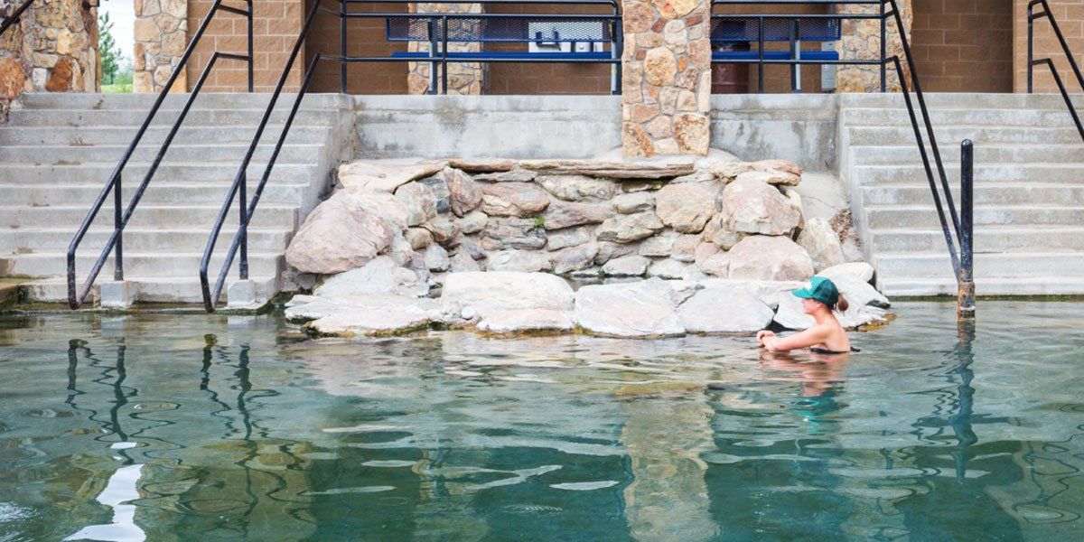A woman is swimming in a pool with stairs leading to it.