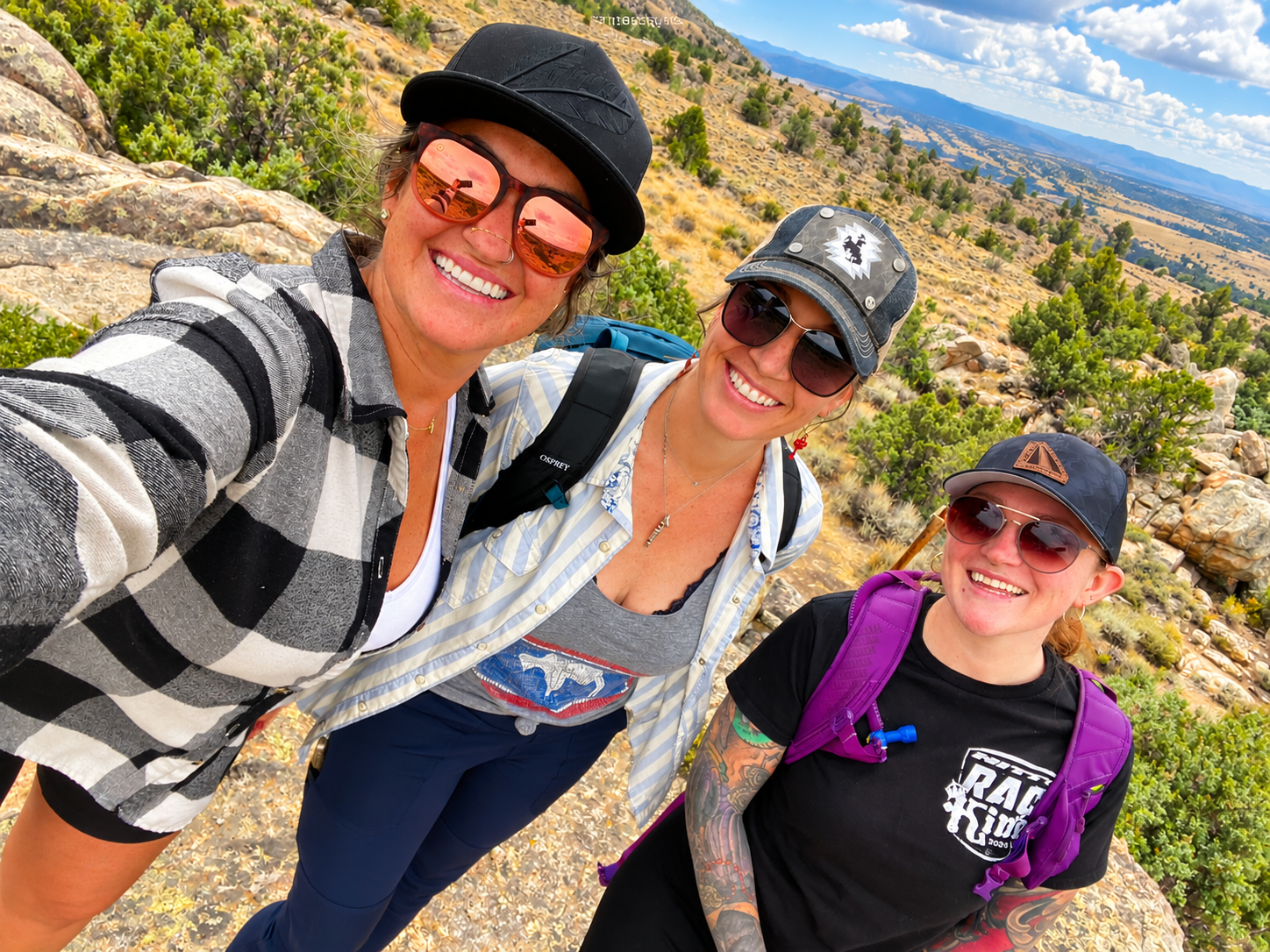 A woman with a backpack and hiking poles is walking up a hill.